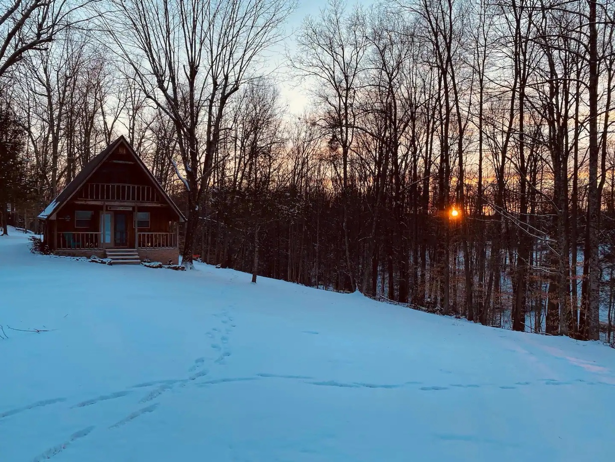 Cabin in winter with golden sunset through the trees